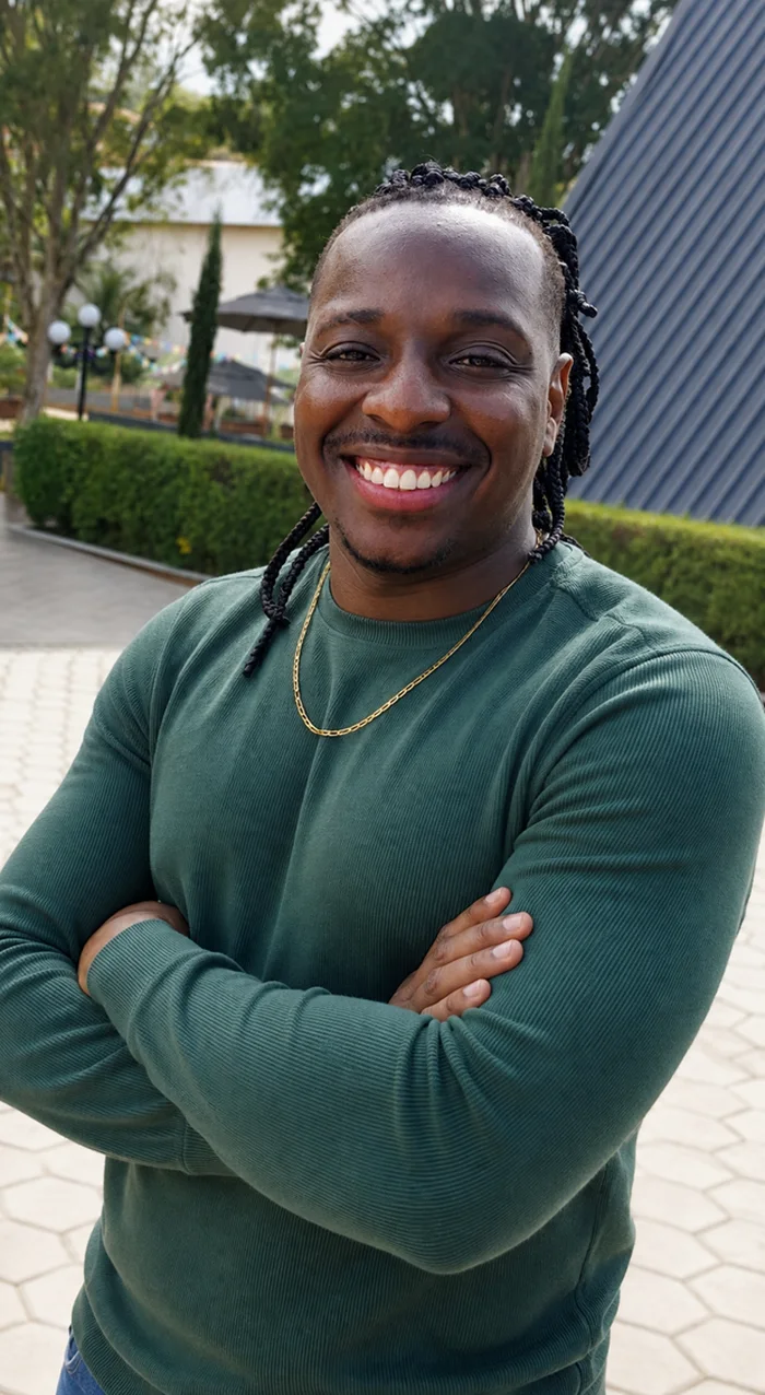 Higor Gama de braços cruzados, sorrindo, ao ar livre