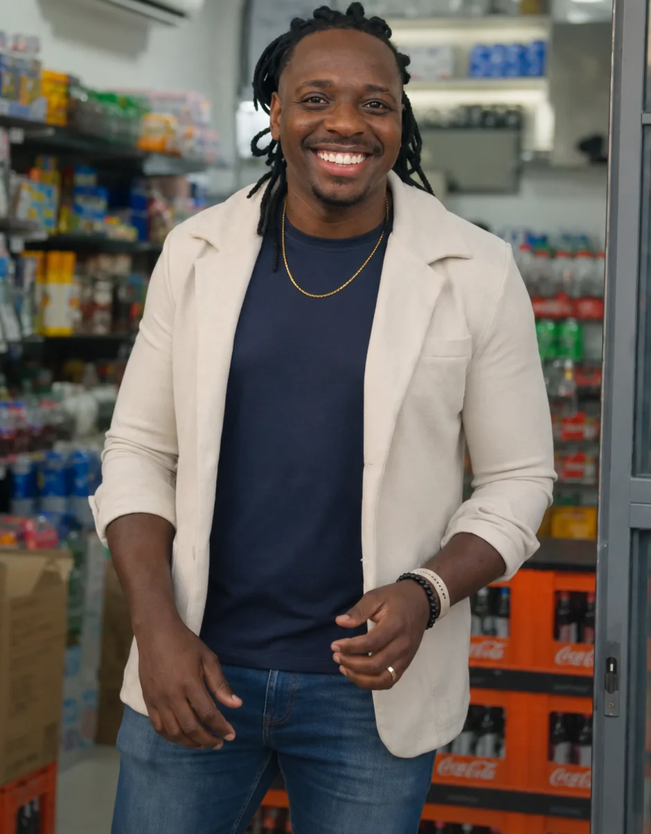 Higor Gama sorrindo na porta do comércio, de blazer claro